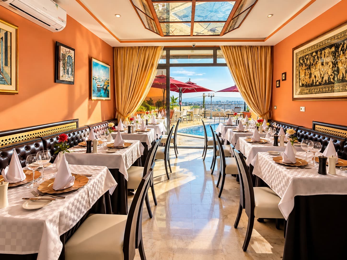 Salle de restaurant aux murs orangés ouverte sur la piscine et la terrasse