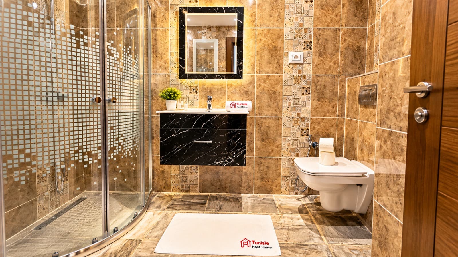 Salle de bain en marbre brun, meuble vasque noir veiné et douche d'angle vitrée